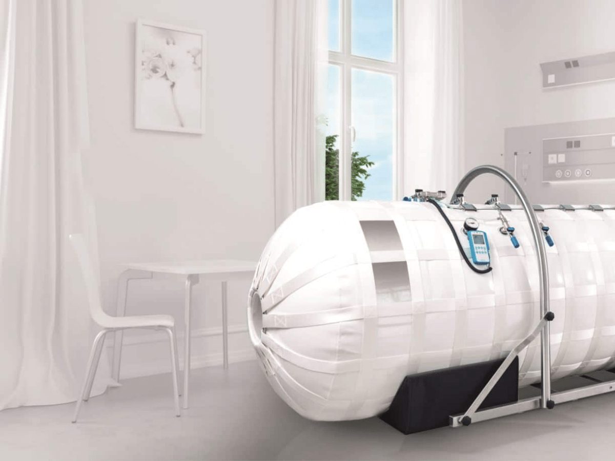 Compact home hyperbaric chamber mounted on a wall in a studio apartment